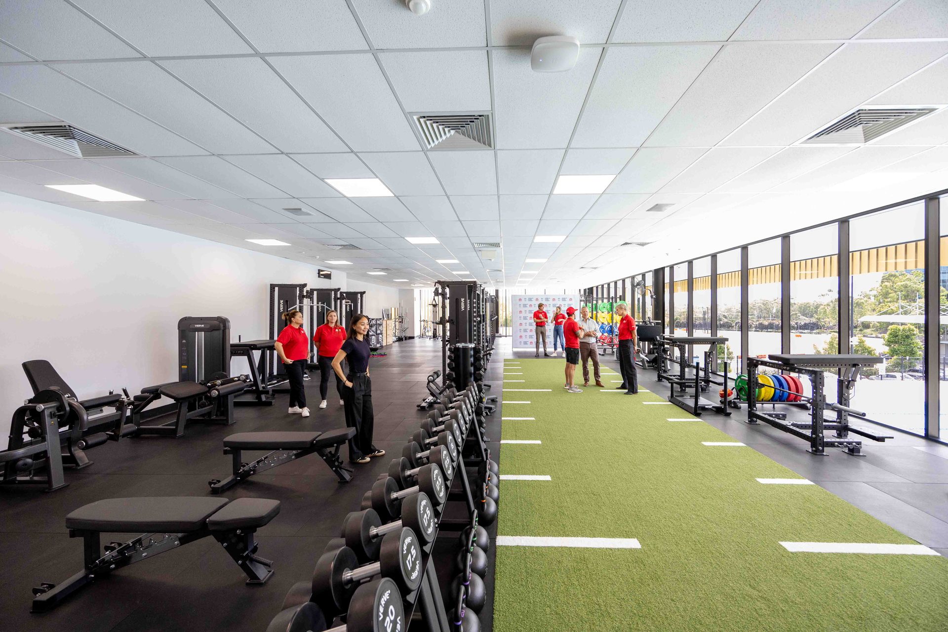 The 600 square metre strength and conditioning floor VERVE designed and installed at Griffith University's High Performance Hub — colour-coded rigs, turf track and floor-to-ceiling glazing.